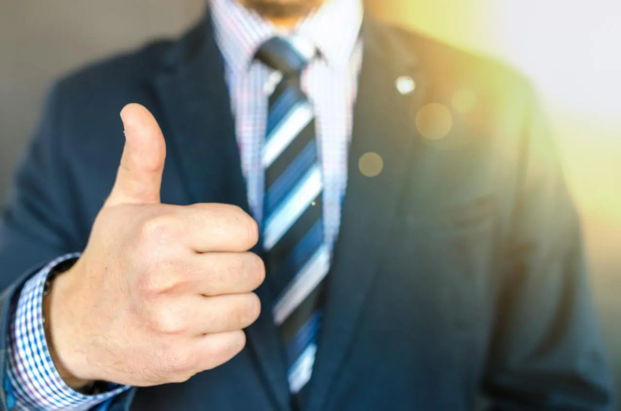 person dressed in suit and tie, holding up a thumbs up sign - what makes a good witness