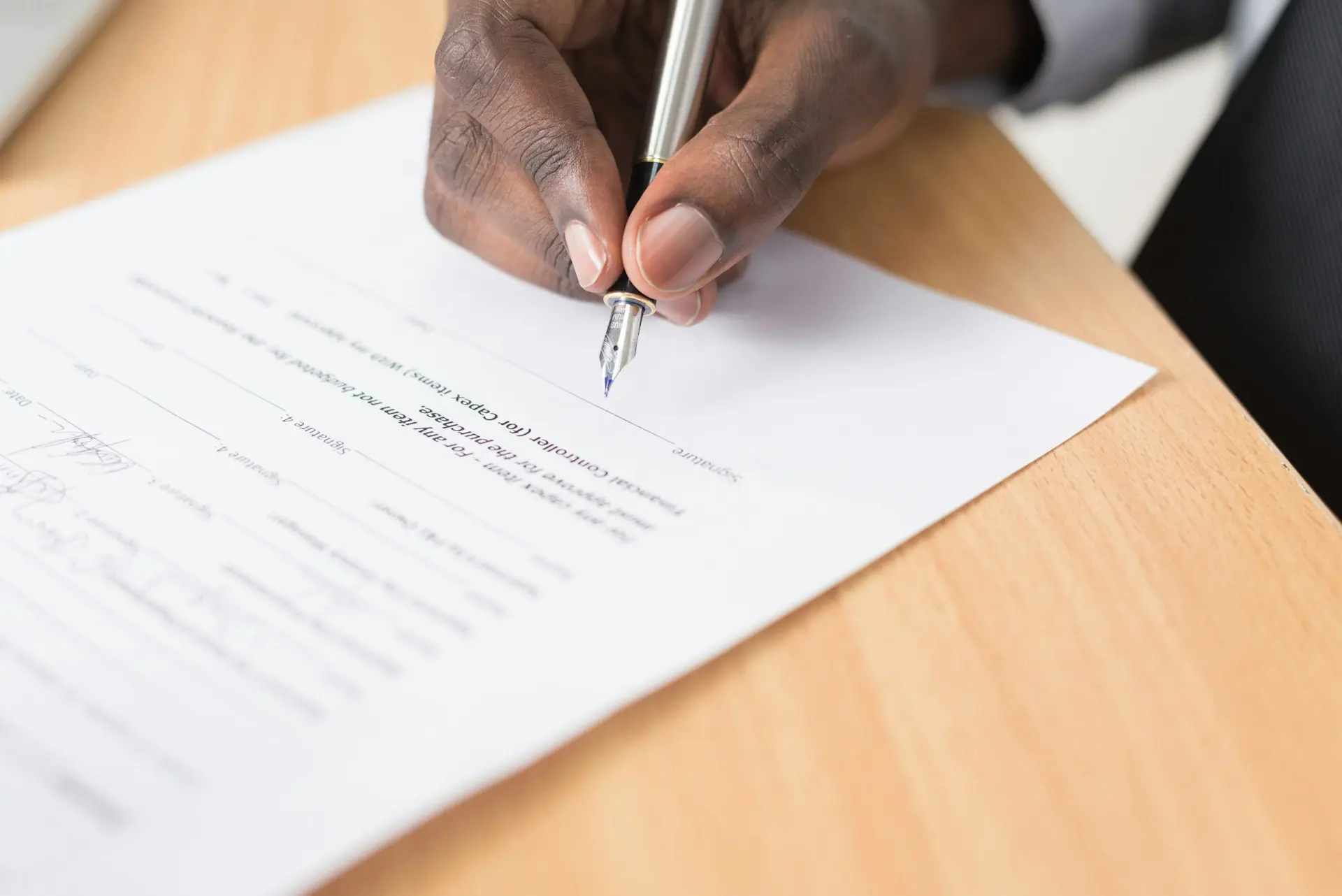 a hand holding a pen about to sign a paper