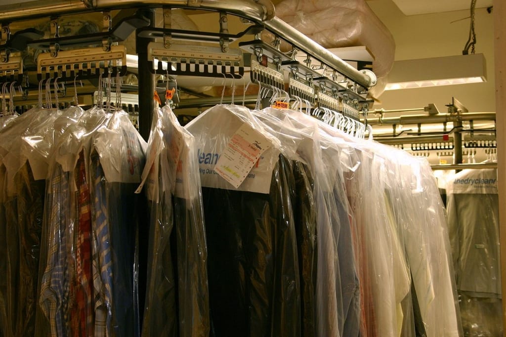 multiple shirts hanging from a dry cleaning line