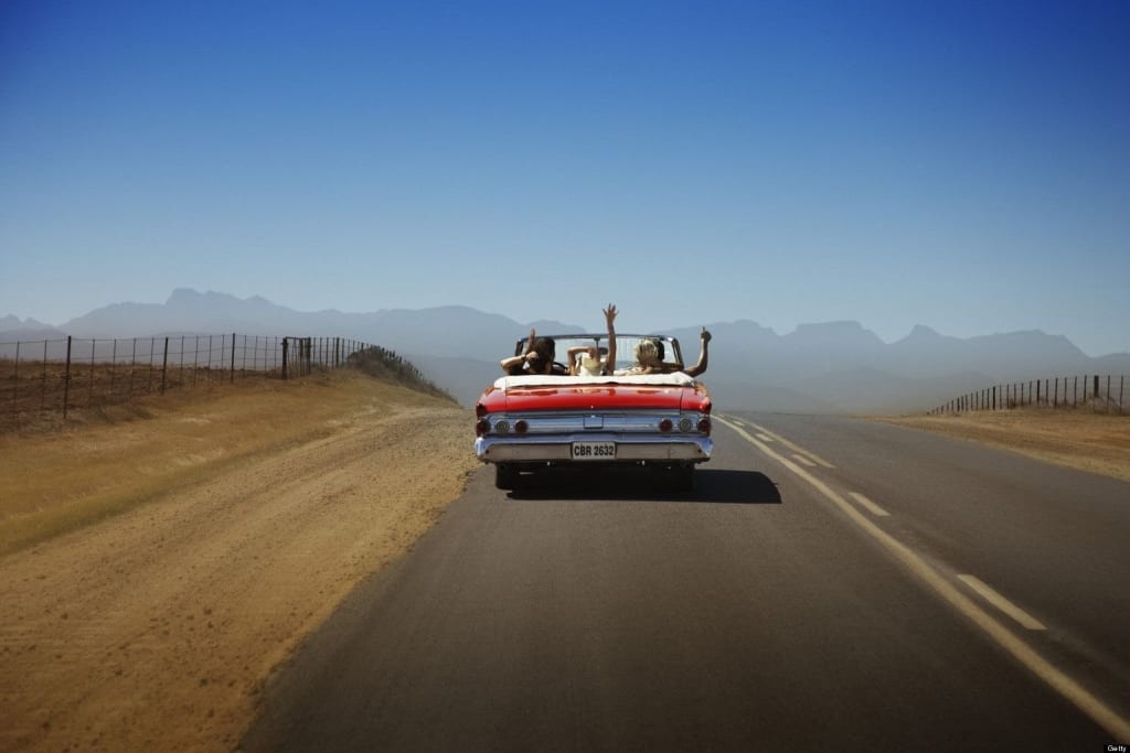 People on road trip riding in convertible car