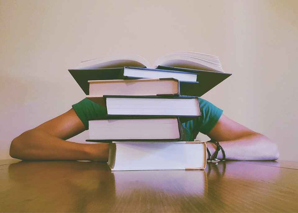 student behind pile of books