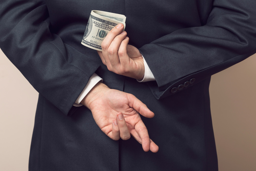 businessman holding money with fingers crossed behind back