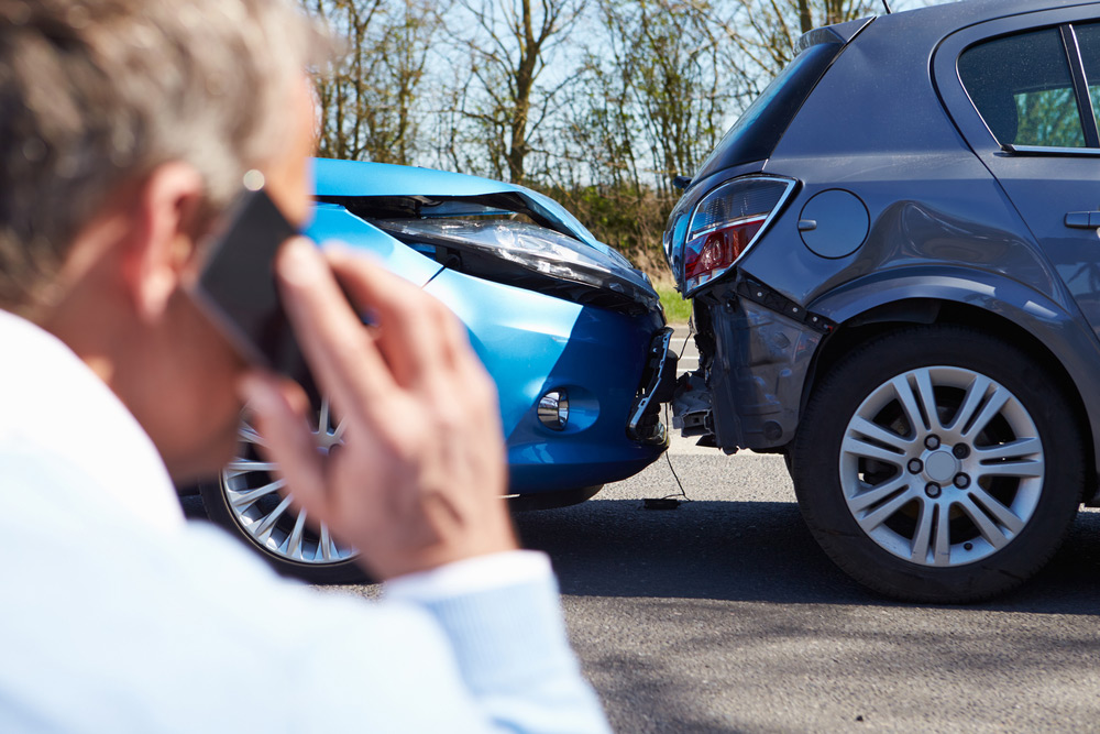man on phone looking at car accident
