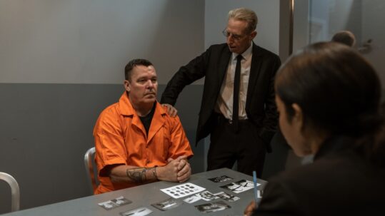 man in orange jumpsuit being interrogated