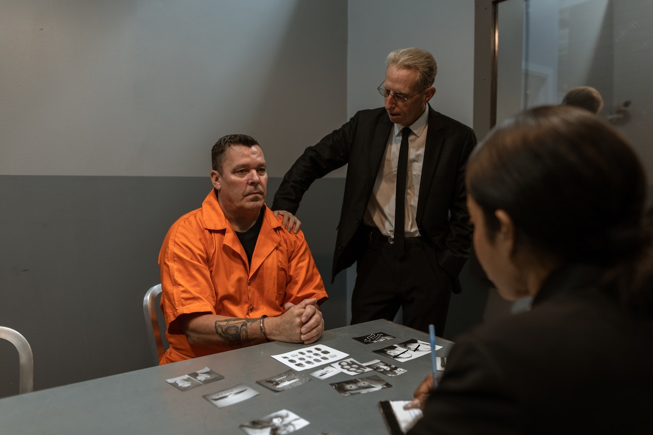 man in orange jumpsuit being interrogated