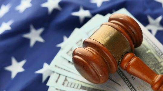 gavel sitting on cash and american flag