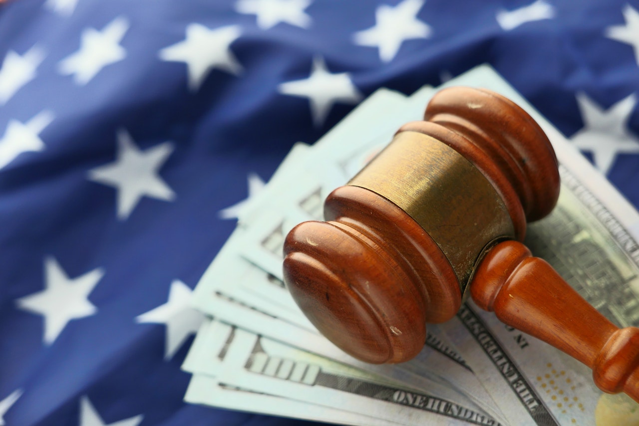 gavel sitting on cash and american flag